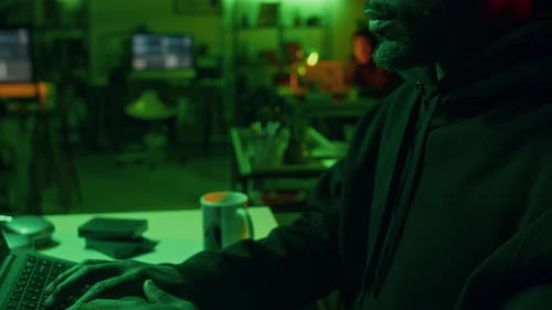 Millennial Cybercriminal Coding on Laptop Committing Malicious Activities