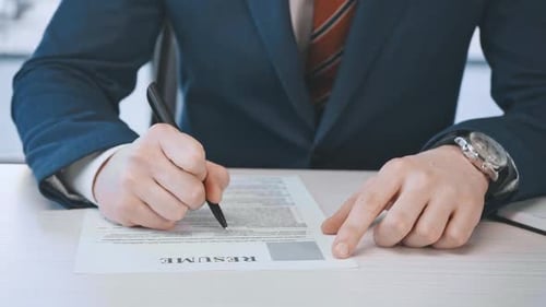 cropped view of man filling and signing document with resume lettering in office