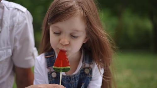 Little Girl Enjoys Watermelon Lollipop Outdoors