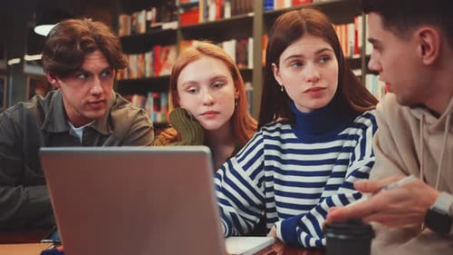 Schüler arbeiten in der Bibliothek über Laptop zusammen
