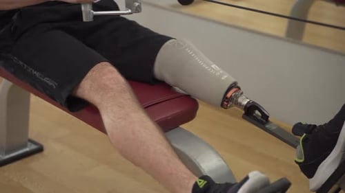 Disabled Athlete with leg prothesis make heavy workout at the gym