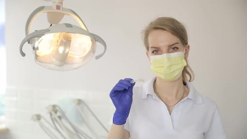 Woman Dentist Holding Clear Dental Aligner in Clinic