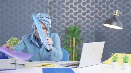 Hijab business woman looking for documents at the table.