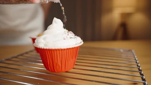 Adding Sprinkles to a Cupcake with White Frosting