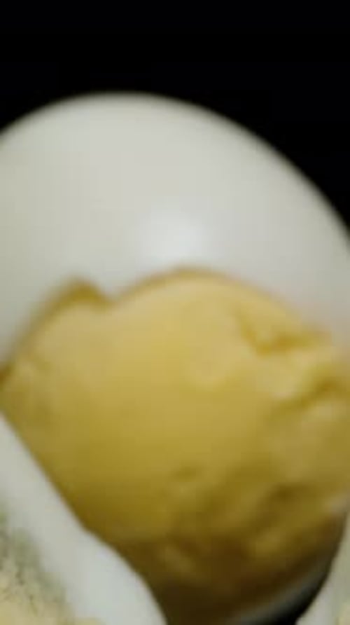 Vertical video. Boiled Chicken Eggs Cut in Half, on a Black Table. Dolly Slider, Close Up.