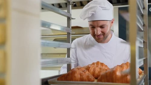 Baker Smiling at Tray of Fresh Croissants