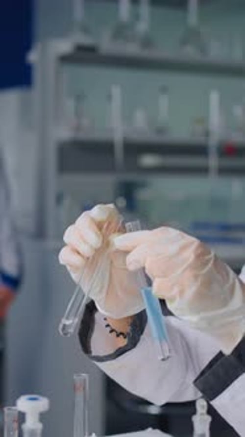 Scientist Mixing Chemical Solutions in Glass Test Tubes