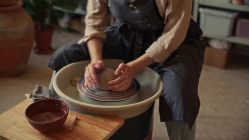 Female Artisan Pressing Clay on Pottery Wheel in Workshop