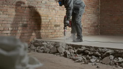 Construction Worker Using Jackhammer to Break Concrete Floor