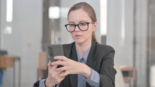 Worried Woman Looking at Smartphone in Office
