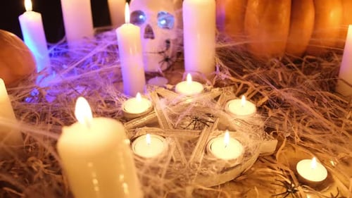 Creepy autumn holiday decor with pentagram with flickering candles and traditional pumpkins