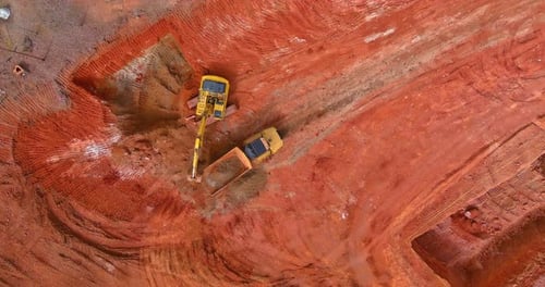 Excavator Filling Dump Truck on Construction Site Aerial