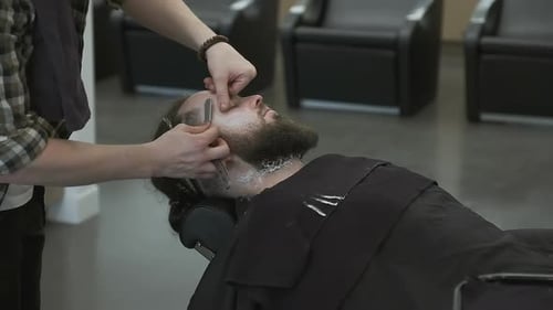 Man Relaxing During a Beard Shave at Barber