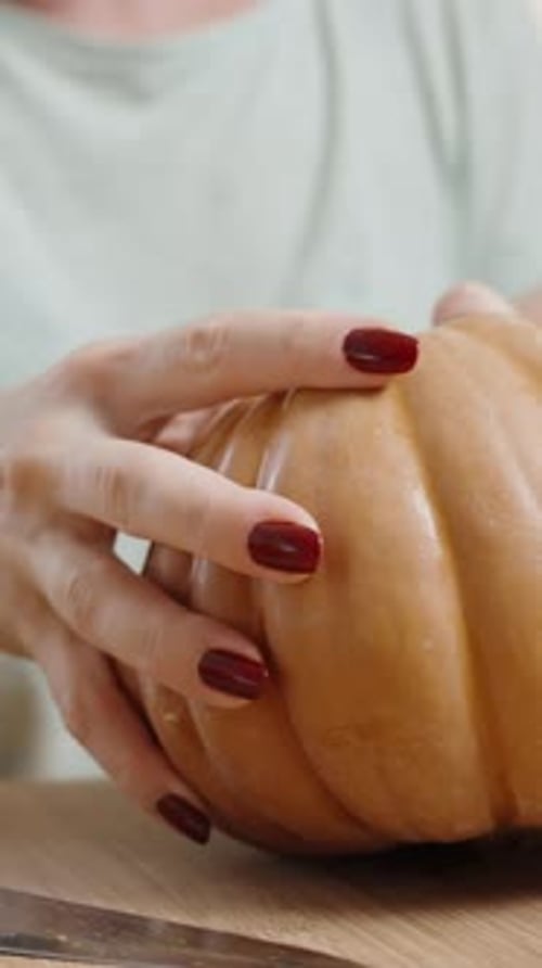 Vertical video. A Woman Tears a Small Pumpkin in Half with Her Hands. She will then slice.