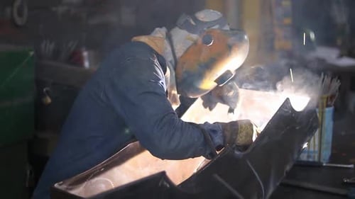 Worker Welding Metal in Factory with Safety Gear