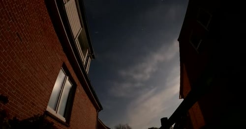 Night Time lapse of a bright moon shadows on a house wall, clouds moving in the sky, in Germany