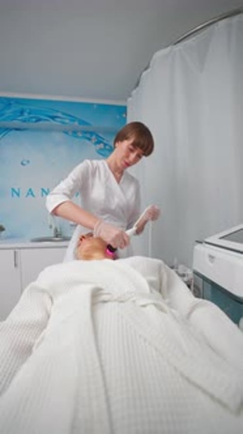Young Adult Female Beautician Doing RF Face Lifting Procedure