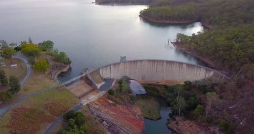 Aerial top view of lake Moogera dam with water falling at sunset - Queensland, Australia.