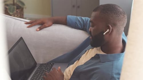 Man Working On Laptop While Relaxing On Sofa