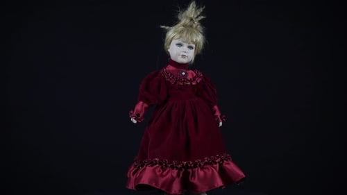 Blonde Antique Doll In Red Dress On Black Background.