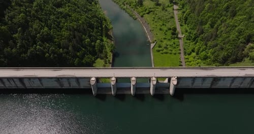Dam and water reservoir, panoramic aerial top view. Tracking drone shot, sunny day