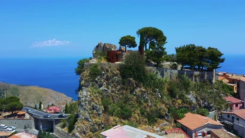 Drone flying around the remains of an old castle on the small rocky cliff surrounded by the Sicilian