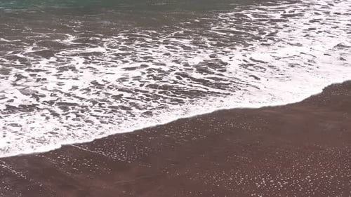Waves gently meeting the shore at a serene beach during the golden hour