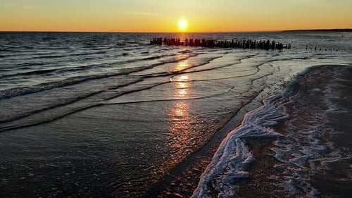 Old pier beautiful sunset over a calm ocean. The sky is ablaze with fiery oranges, pinks, and purple