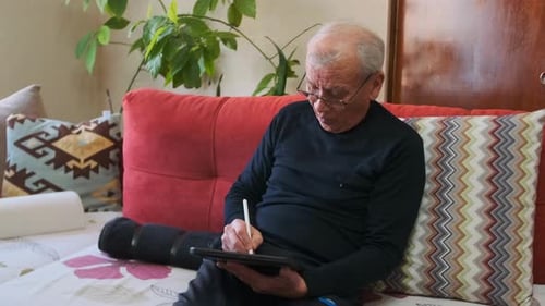 Senior Man Using Tablet on Couch in Home