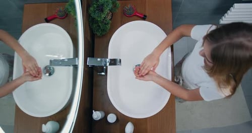 To view of a little girl who washes and soaks her hands with soap in modern bathroom at home.