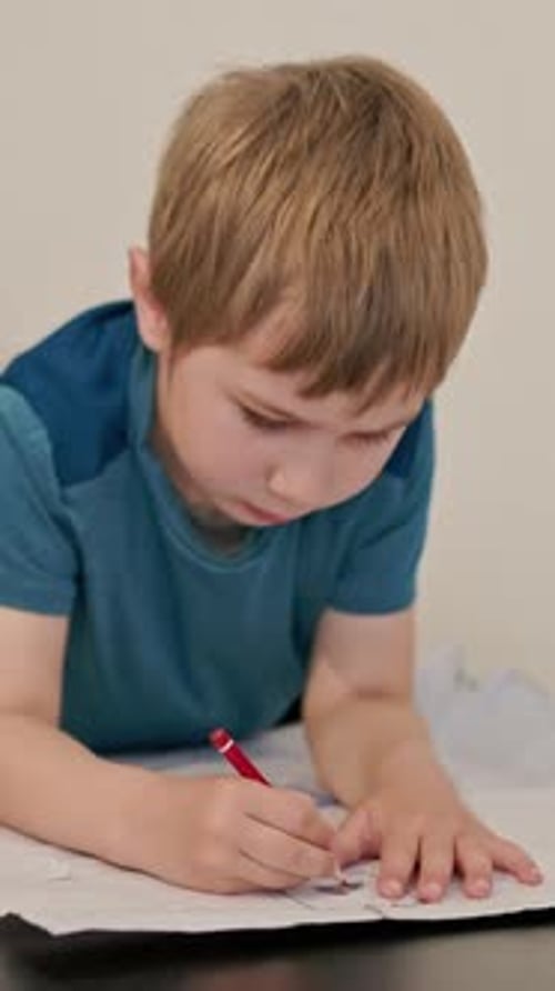 Young Boy Drawing on Paper with Colored Pencils at Table