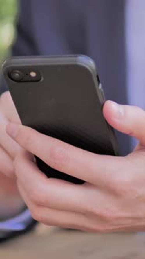 Man Holding and Using Black Mobile Phone