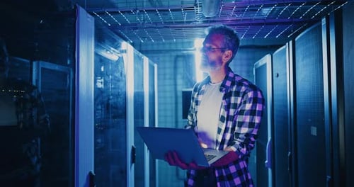 Man Working on Laptop in Server Room