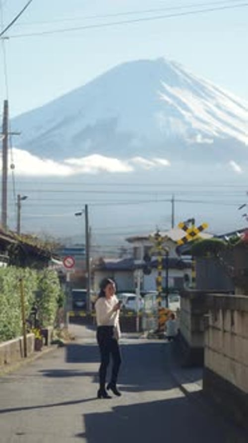 4K Asian woman using mobile phone taking picture of mt Fuji covered with snow