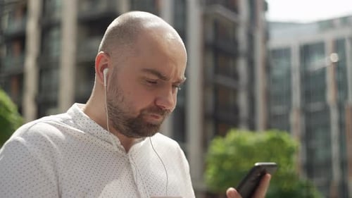 Man Using Smartphone with Headphones in City