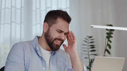Man Experiencing a Headache at his Desk