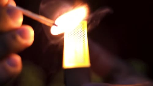 Hand Striking a Match in the Dark
