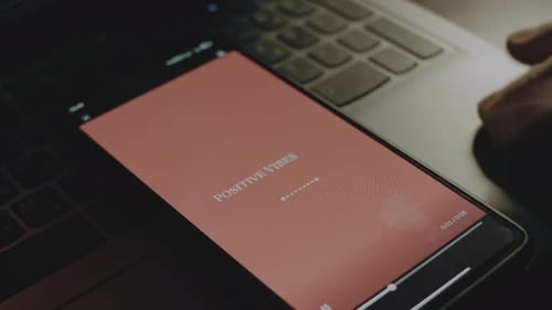 La inscripción Positive Vibes Only sobre fondo rosa en la pantalla del smartphone proviene de rayos de luz