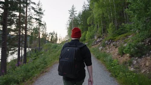 Back View of a Man Walking in the Forest a Backpack Hanging on His Back a Red Hat
