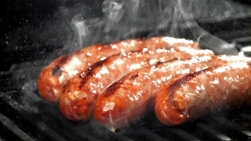 Grilled Sausages sizzling on barbeque grill with smoke