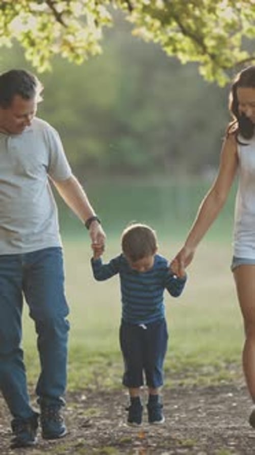 Cute Young Family Walking in the Park Parents Holding Their