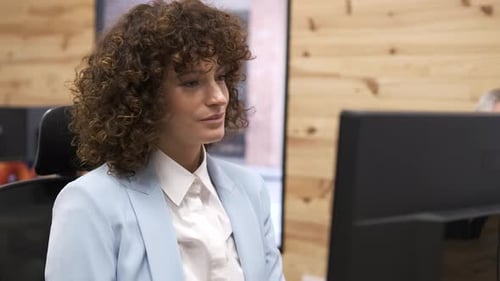 Confident Businesswoman with Curly Brunette Hair Using Computer in Office