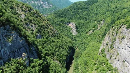 A view from above shows a river flowing through a valley. Tall cliffs line both sides of the river.
