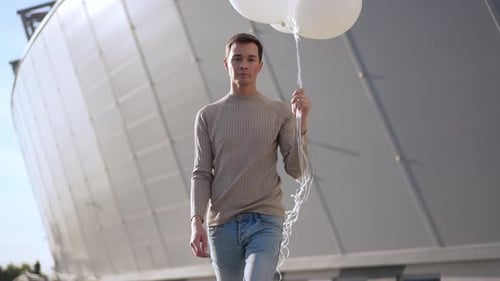 Young Adult Carries White Balloons in Urban Setting