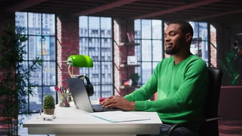 African American Male Teleworker Completing Spreadsheets on Laptop