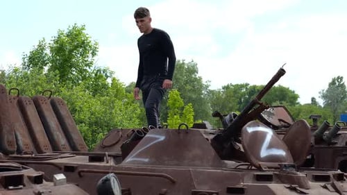 Young Adult Walks on Rusted Military Tanks