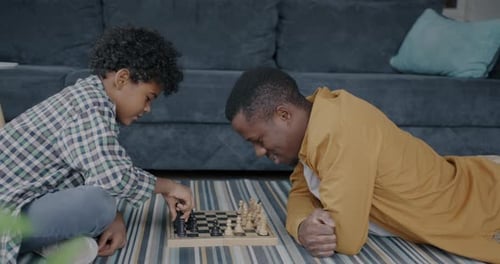 Side View of Dad African American Man Playing Chess with Little Boy Teaching Kid Intellectual Game