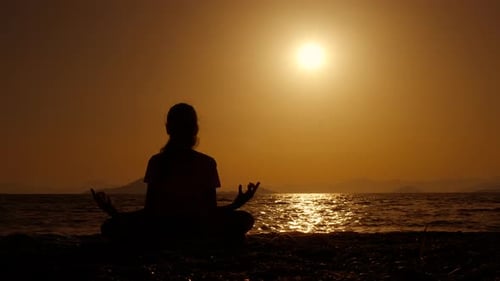 Silhouette Meditating on Beach at Sunset