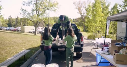 Youth Volunteers Load Paint Cans into Truck Bed