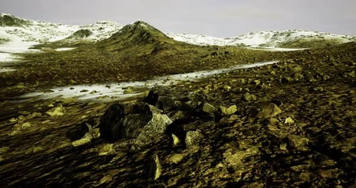 Vast Rocky Terrain with Distant Snow Capped Mountains Under a Cloudy Sky